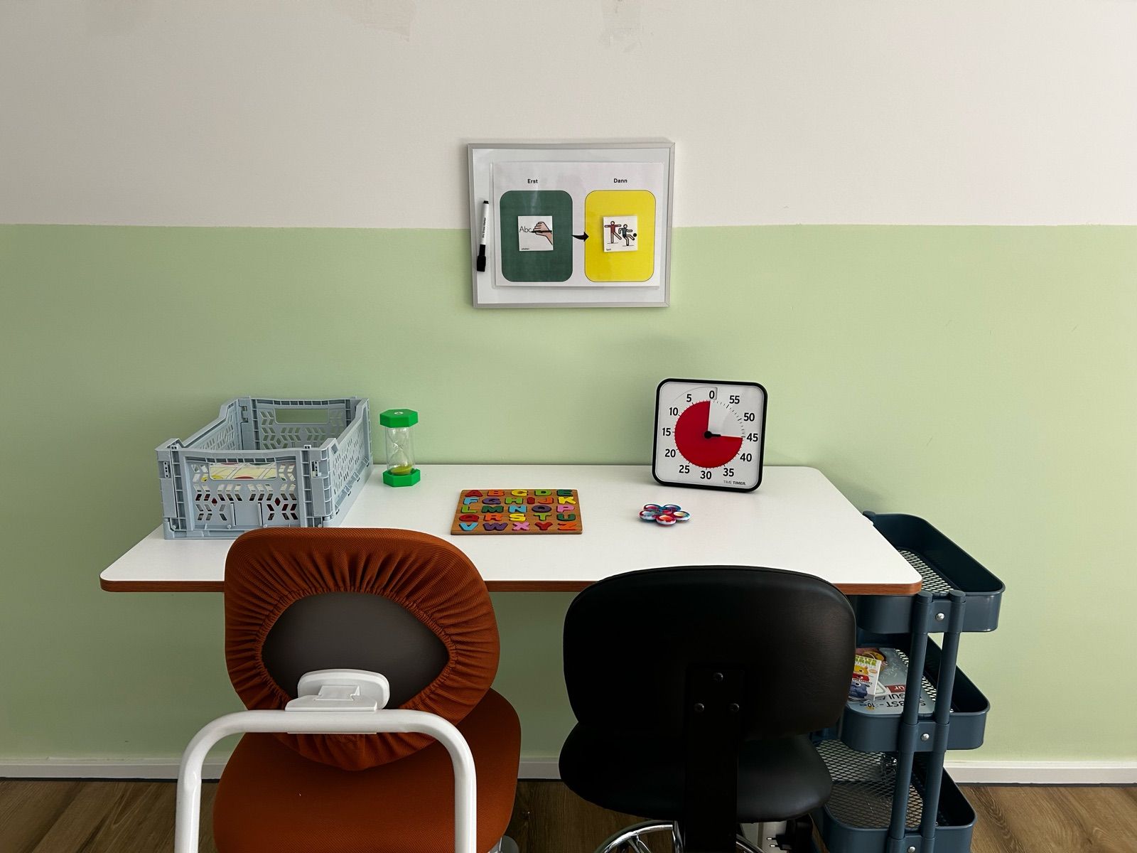 Arbeitstisch im Gruppen- und Strukturraum mit Erst-Dann-Plan, Time Timer und Buchstabenpuzzle